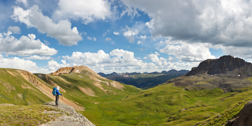 panoramic view of the colorado rocky mountains with hiker in all blue in forefront